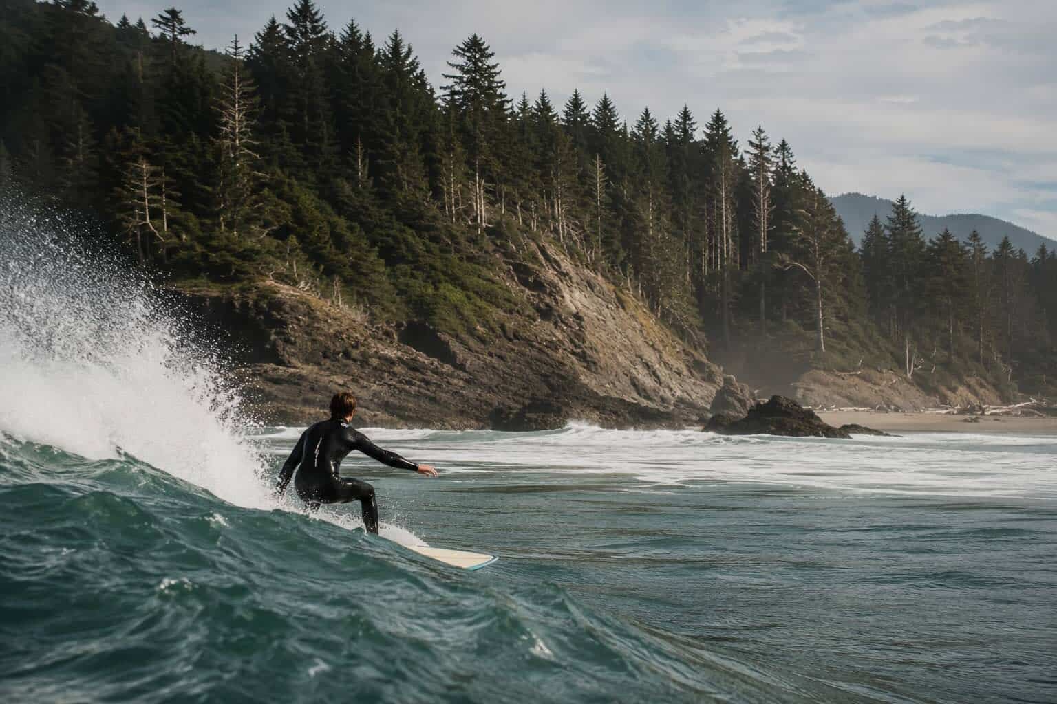 Surfer catching a wave at a rugged, off-grid beach on North Vancouver Island.