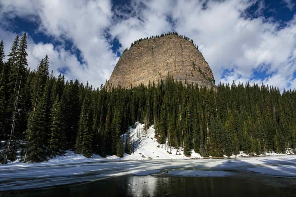 A massive mountain peak towering above a frozen lake in the Canadian Rockies