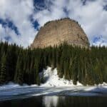 A massive mountain peak towering above a frozen lake in the Canadian Rockies